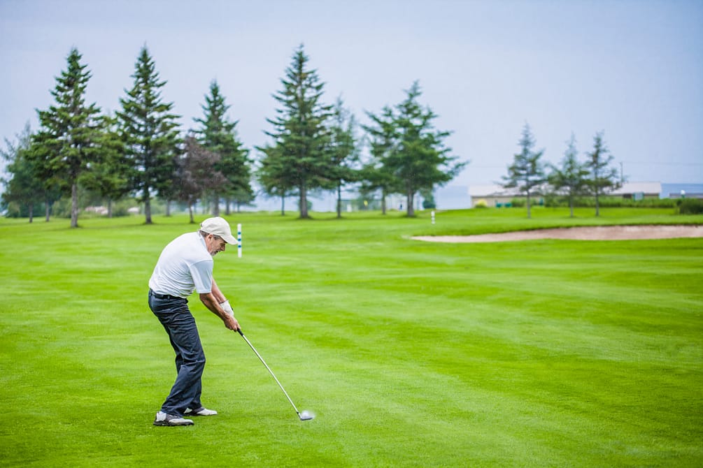 Mature Golfer on a Golf Course Hitting a Ball (moment of the impact)