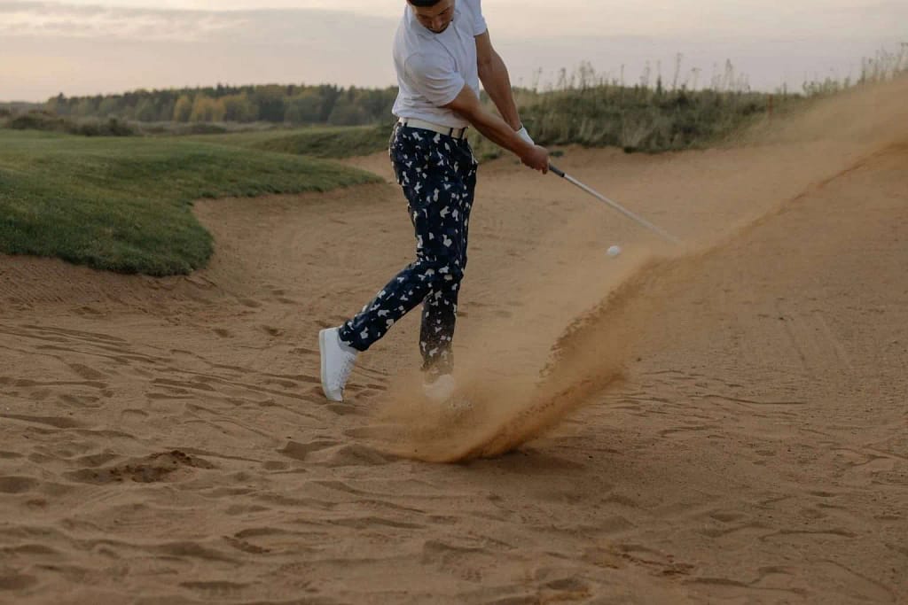 A golfer using sand wedge to ger bounce to hit the golf ball