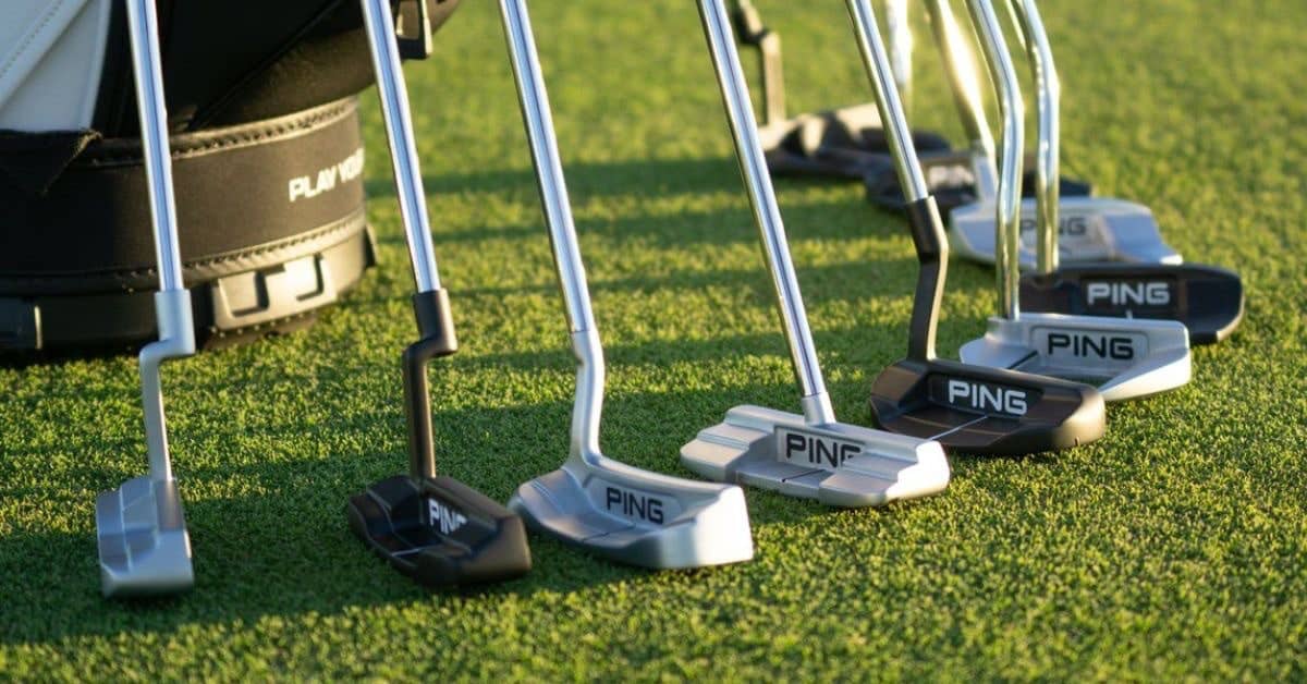 different types of putter heads aligned in a green grass lawn