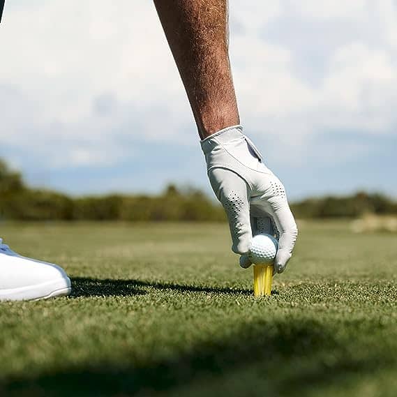 A golfer placing golf ball in a brush tee