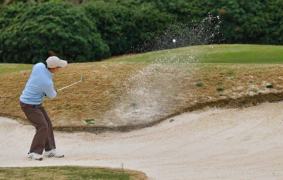 A golfer hitting golf ball with sand wedge to get the ideal bounce